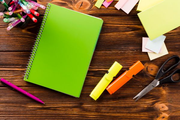 Un cahier vert sur un bureau de bois.